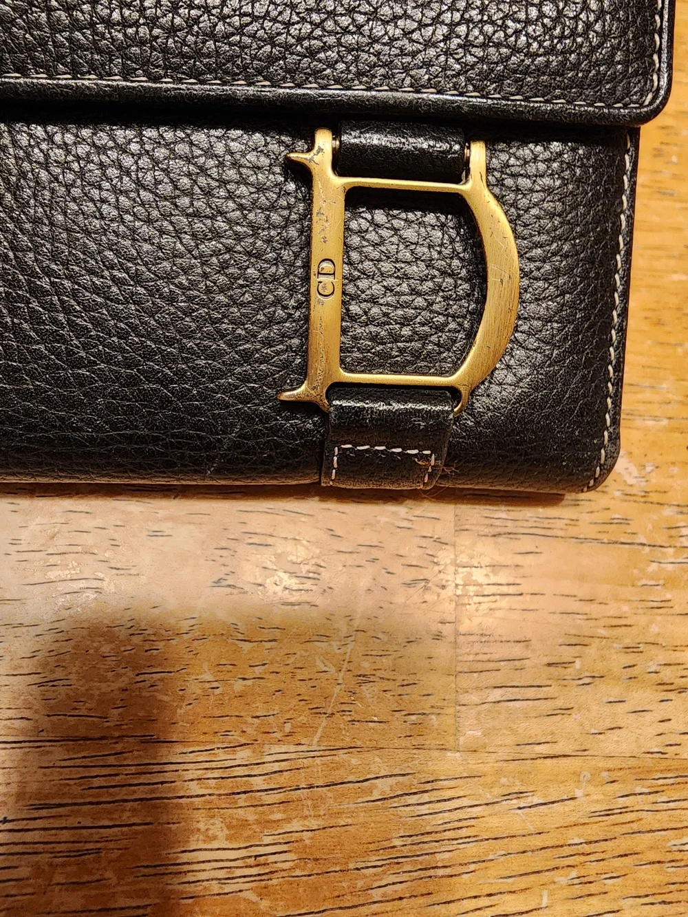 black Christian Dior pebbled leather trifold long wallet featuring gold-tone 